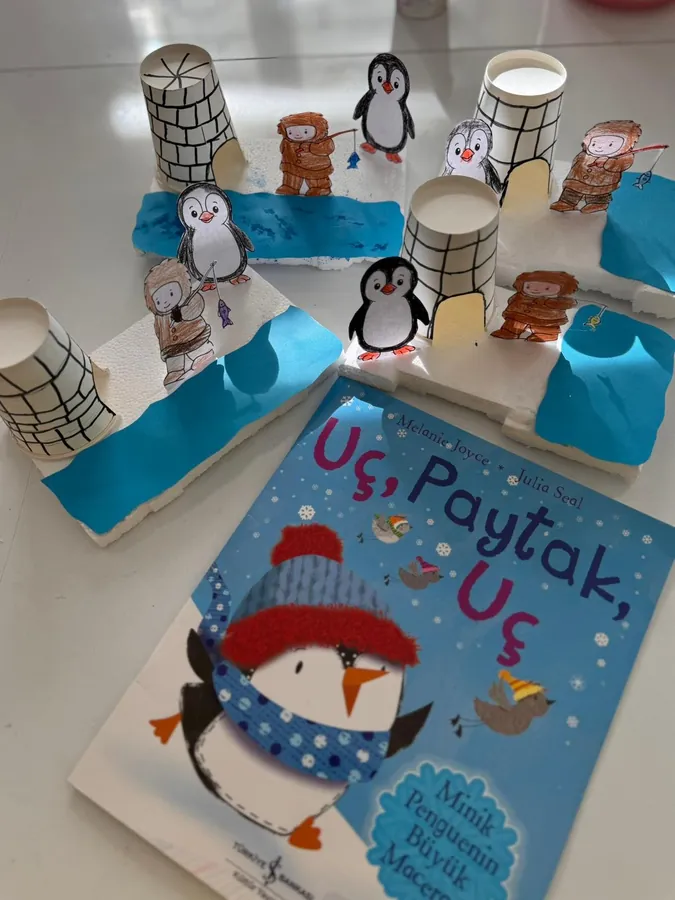 Paper-cup igloo and penguin model next to a picture book