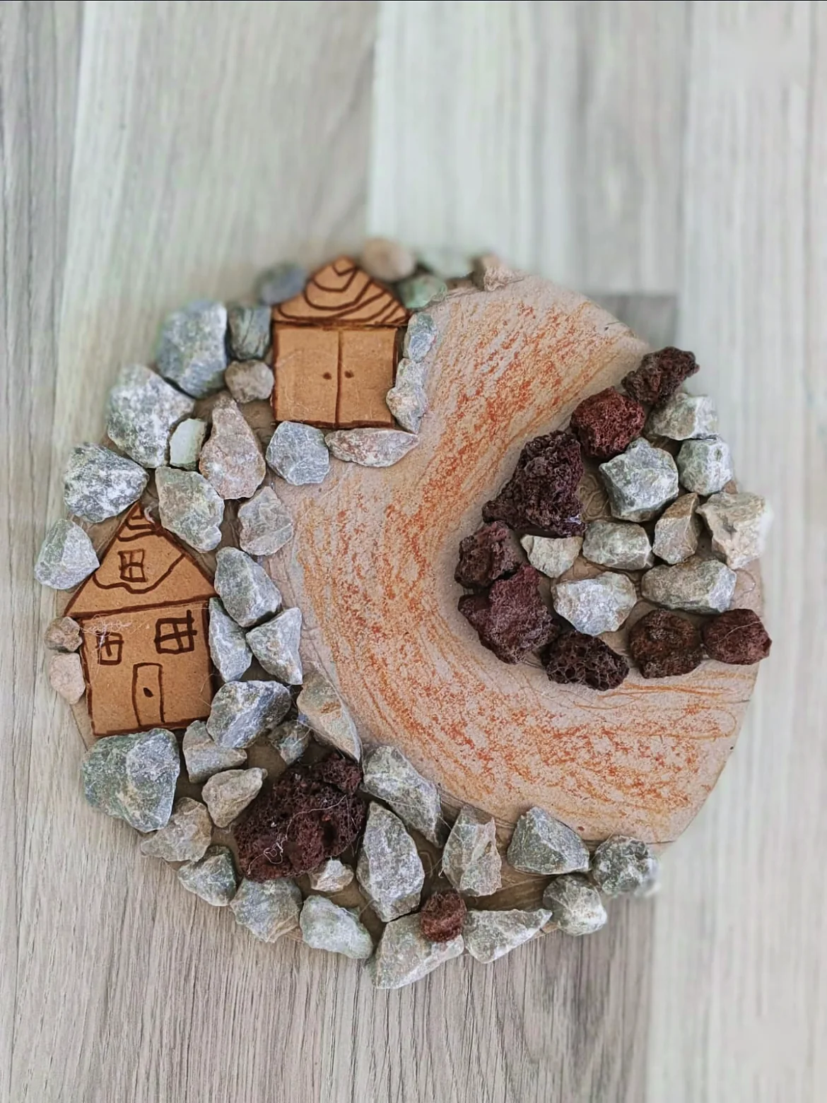 A village and road made with stones and drawn houses on card